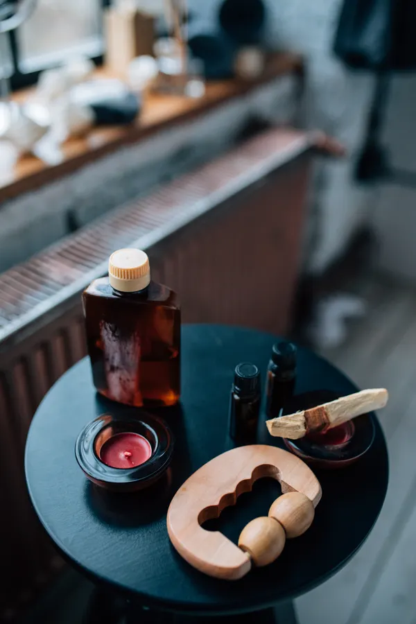 Illustrative stock photograph of amber massage oil, candles and wooden massage tools