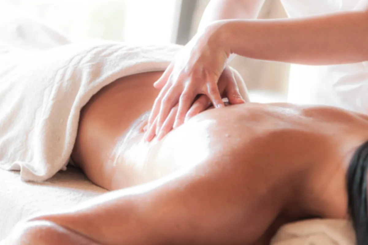 Illustrative stock photograph of a soothing oil massage with fresh white towels and soft natural light